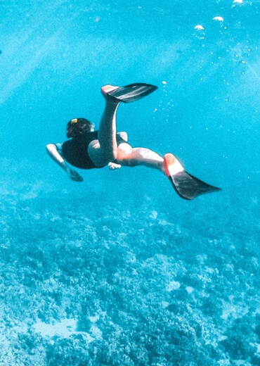 На фото девушка в море плывет под водой