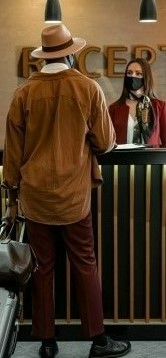 На фото мужчина стоит на ресепшене и бронирует себе место в отеле
