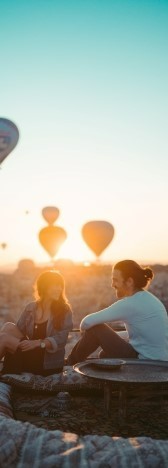 На фото мужчина с девушкой разговаривают и смеяться на фоне воздушных шаров