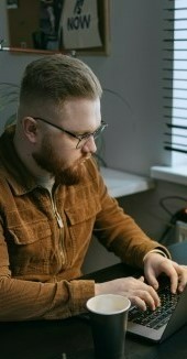 На фото мужчина работает через ноутбук у себя в комнате