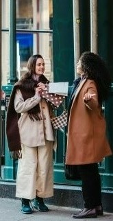 На фото две знакомые девушки встретились на улице и пошли по магазинам