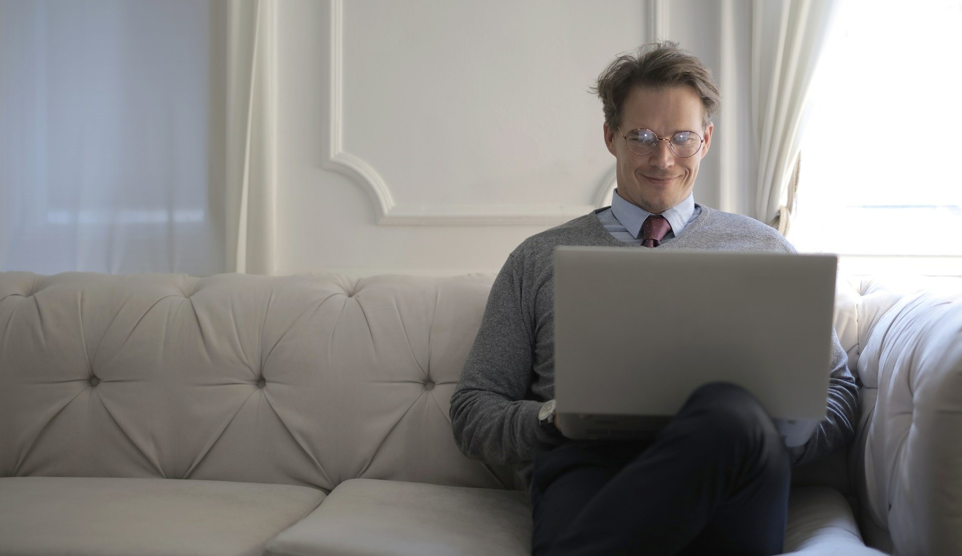 Фото с мужчиной в комнате сидящий на диване перед ноутбуком